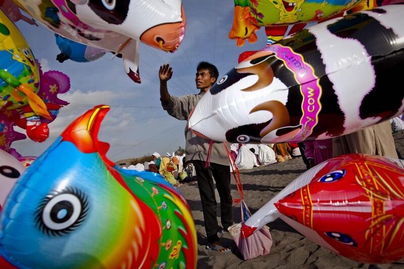 A man sells balloons as Muslims in attend Eid Al Adha prayers at Parangkusumo beach.