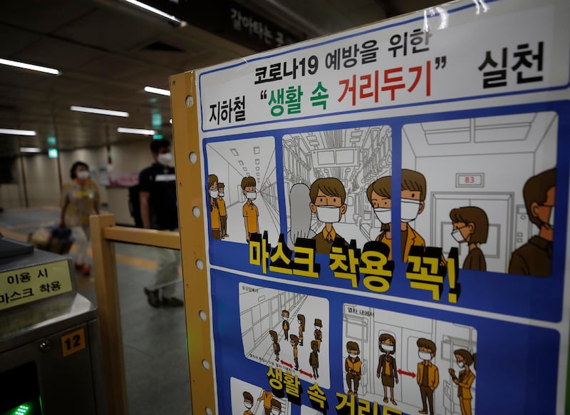 Passengers wearing face masks walk near a banner displaying precautions against the coronavirus at the subway station in Seoul, South Korea. AP Photo