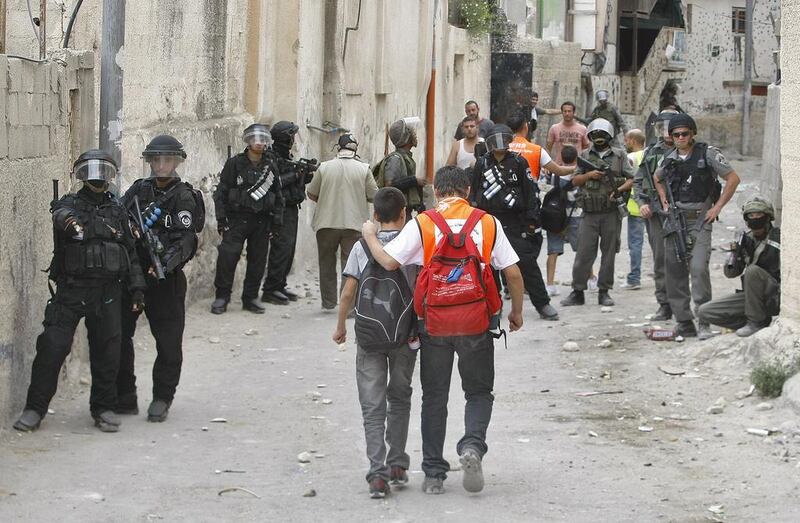 Palestinian school children walk past Israeli riot police during clashes with masked youths on September 22, 2010. AFP Photo