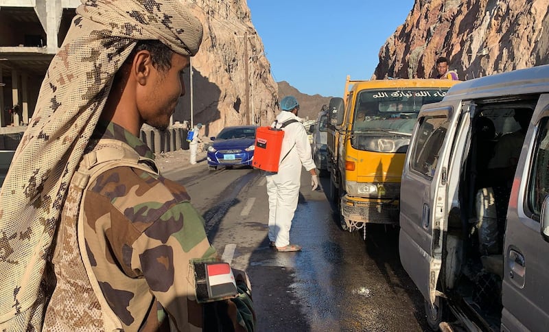 Members of Yemen's separatist Southern Transitional Council (STC) man a checkpoint while workers disinfect vehicles at the entrance of Mualla, a district of the southern province of Aden, amid the COVID-19 pandemic on May 10, 2020.  / AFP / -
