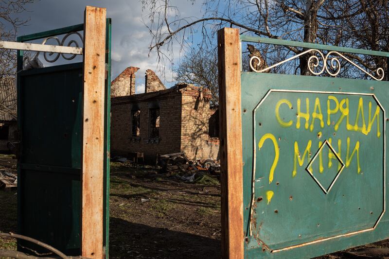 A writing on the gate of a destroyed building in Andriivka - 'Shells, mines?' - points to the threat faced by Ukrainians. Getty Images