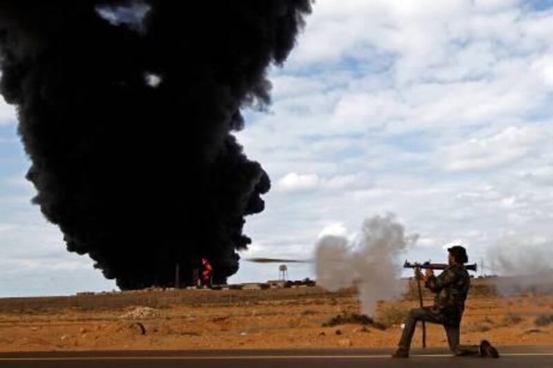 A rebel fighter fires a rocket-propelled grenade launcher in front of a gas storage terminal during a battle on the road between Ras Lanuf and Bin Jiwad, March 9, 2011. The rebel movement in their east Libya headquarters of Benghazi said on Wednesday their forces moved back into the hard fought over town of Bin Jawad, but some fighters said its fate was not clear.
  REUTERS/Goran Tomasevic (LIBYA - Tags: POLITICS CIVIL UNREST IMAGES OF THE DAY) *** Local Caption ***  GOT01_LIBYA-EAST BI_0309_11.JPG