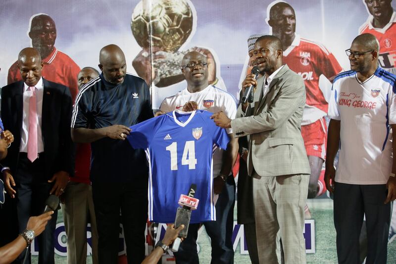 George Weah receives his  jersey from Mustapher Raji, President of the Liberia Football Association, and Joegar Wilson, Minister of Youth and Sports. EPA