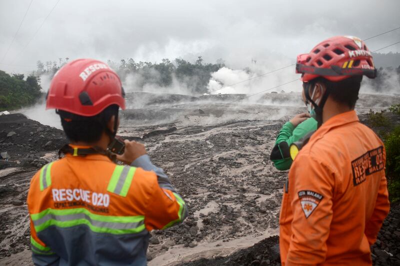 Rescuers monitor the flow of volcanic materials from the eruption of Mount Semeru. AP