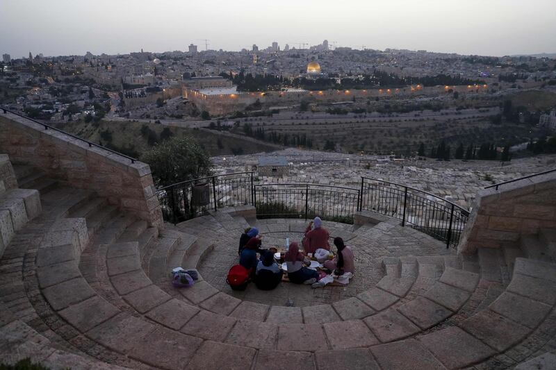 Palestinians gather to break their fast during the Muslim holy month of Ramadan, at the Mount of Olives with a backdrop of the Old City of Jerusalem and the closed al-Aqsa Mosque compound, during the novel coronavirus pandemic crisis.  AFP