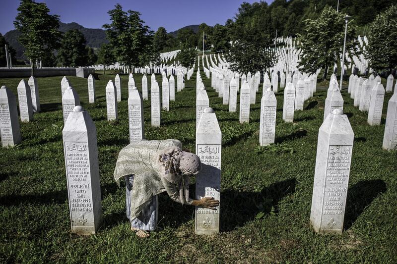 A Bosnian Muslim woman cleans a gravestone of a victim of the massacre at Srebrenica in July 1995, when more than 8,000 Bosnian Muslim men and boys were killed by the Bosnian Serb Army. Getty Images