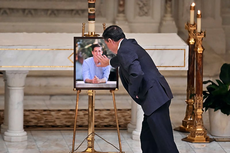 Alex Lucido, a close family friend, touches a portrait of Mr Fraser. AP