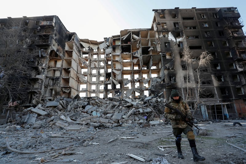 A pro-Russian troop service member walks near a destroyed apartment building in the besieged southern port city of Mariupol. Reuters