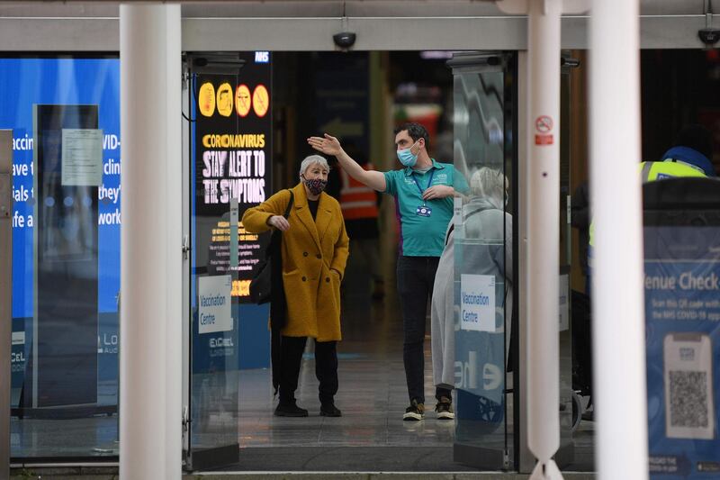 An NHS volunteer directs a woman at the door of the Covid-19 vaccination centre at ExCel London. AFP