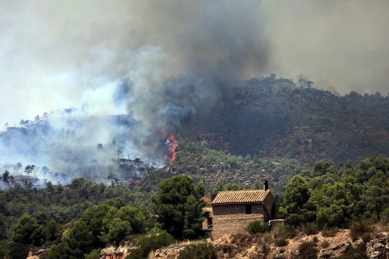 Fire and smoke rise near a house during a forest fire. EPA