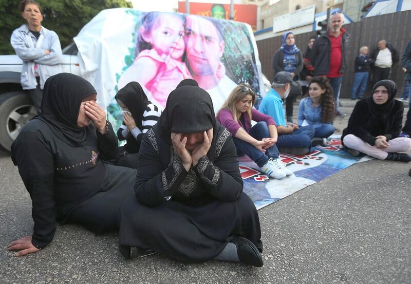 Families of Lebanese security forces who were kidnapped by Islamist militants block a main road during a protest after an Al Qaeda-linked group in Syria claimed it has killed kidnapped police officer Ali Bazzal, seen in poster with his daughter, in Beirut on December 6. Hussein Malla / AP Photo