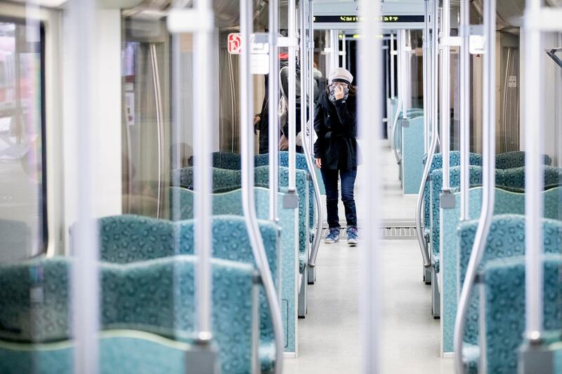 A woman holds her scarf in front of her mouth in an almost deserted suburban train in Berlin.  AP
