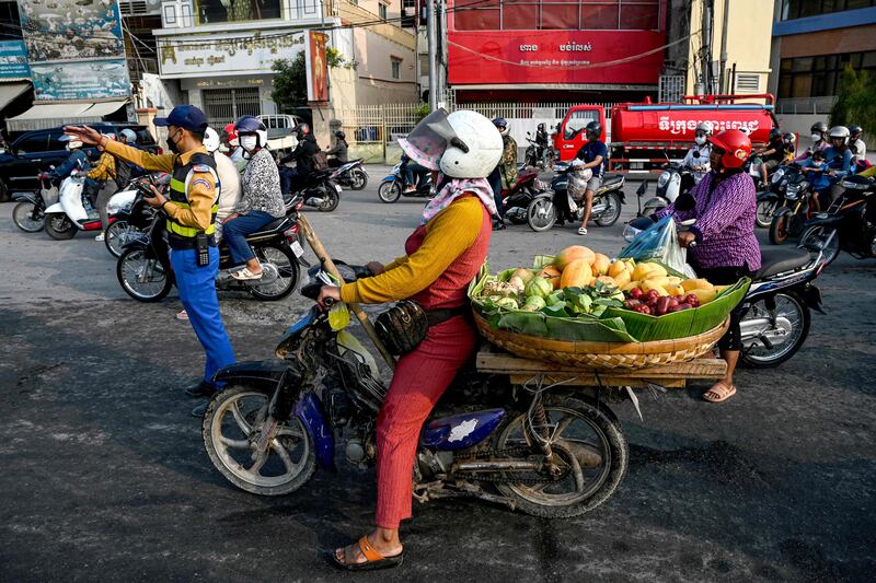 A vendor rides a motorbike loaded with fruits for sale along a street in Phnom Penh. AFP