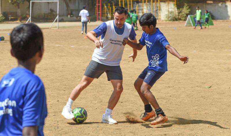 Former Spain international midfielder Xavi plays with Indian children a football game in Mumbai.