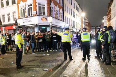 Police officers direct traffic as revellers socialise in the street in Soho, London on July 4, 2020. EPA