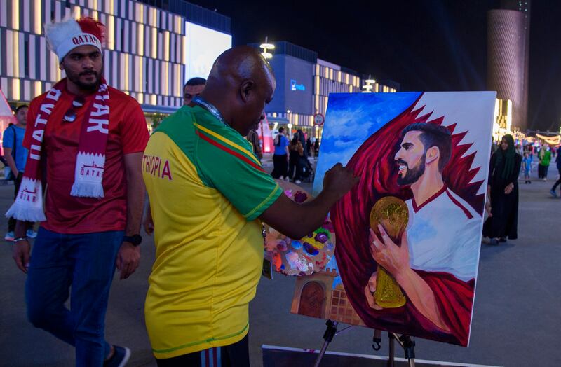An Ethiopian artist paints a picture of Qatari football player Hassan Al-Haydos on the Lusail Boulevard in Doha, Qatar. EPA