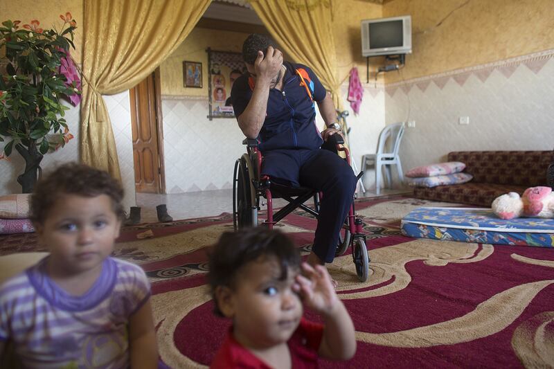 Wael Al Namla at  his home in Rafa,Gaza on July 3,2015 with his daughter Abir (center) and his brother’s orphaned son . He  lost  his the lower part of his right leg during last summer’s war between Israel and the Hamas -controlled Gaza Strip . ‘My life is totally destroyed ‘, said Wael . His wife Azreen lost both her legs, and their son Shareef lost the lower part of his  leg . The incident happened on one of the darkest days during the war that has been named ‘Black Friday’ .The family was fleeing on foot trying to reach a safer area when an Israeli  rocket attack hit them . Wael’s 11 -year old sister and his brother Yousef and his wife were killed . Heidi Levine for The National