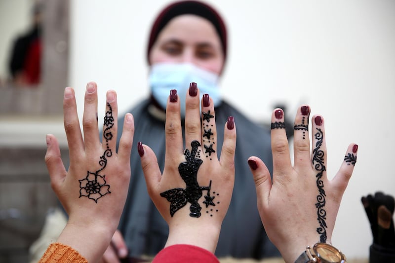 Girls show off henna tattoos drawn by Palestinian henna tattoo artist Samah Sidr, at her shop in the West Bank city of Hebron, in an event to celebrate International Women's Day on March 8. EPA