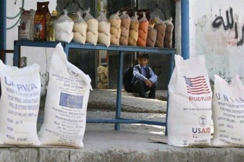 A Palestinian boy sits behind bags of flour donated by various aid agencies as part of their food assistance programs for the people in the Shati refugee camp, Gaza City.