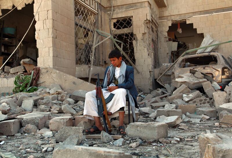 An armed Yemeni youth, loyal to the Shiite Muslim Huthi movement that controls Sanaa, sits amid the rubble on December 5, 2014, guarding the damaged house of the Iranian ambassador in the Yemeni capital which was targeted by a car bomb earlier this week. Al-Qaeda's local branch said on December 3  it was behind a car bombing that killed one person and wounded 17 outside the residence of Iran's ambassador the Yemeni capital, where Tehran is accused of backing Shiite militia.  AFP PHOTO / MOHAMMED HUWAIS (Photo by MOHAMMED HUWAIS / AFP)