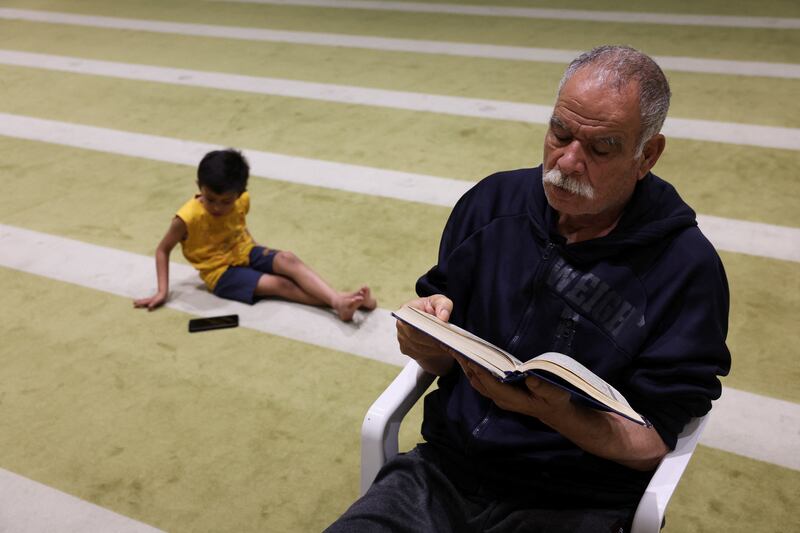 A Palestinian evacuee reads the Quran at a mosque before taraweeh prayers in Emirates Humanitarian City. Reuters