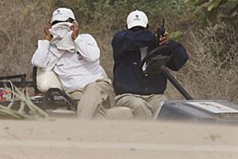 Staff members at the Emirates Golf Club cover up during a sandstorm at the Dubai Ladies Masters Pro-Am yesterday.