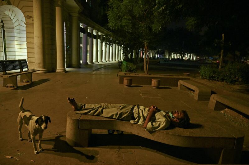 A homeless man sleeps on a bench in Connaught Place during a lockdown imposed to curb the spread of the Covid-19 coronavirus in New Delhi on April 29, 2021. (Photo by TAUSEEF MUSTAFA / AFP)