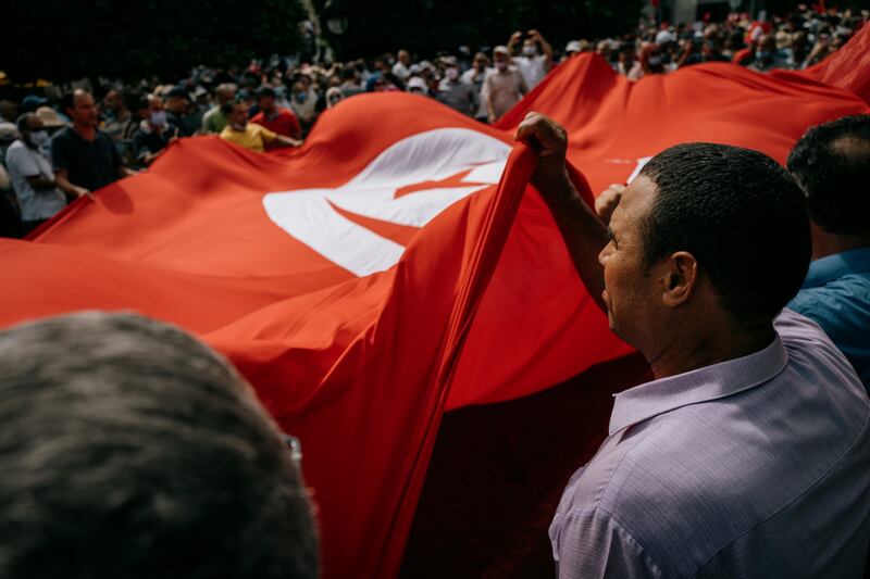 The crowd carry a giant Tunisian flag.
