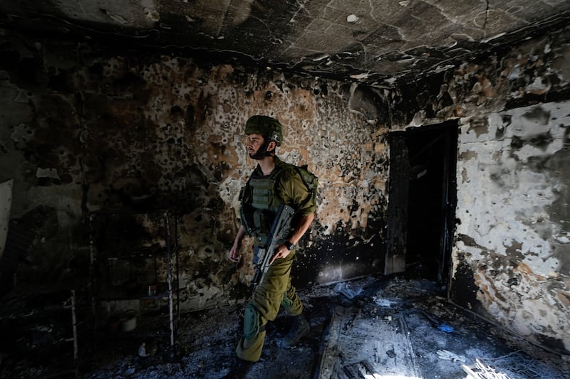 An Israeli soldier inspects a house damaged by Hamas militants in Kibbutz Kfar Azza, Israel. AP