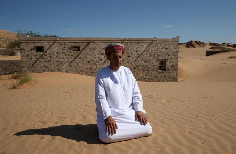 Mohammed al-Ghanbousi, a former inhabitant of Wadi al-Murr, kneels to pray on a sand dune among abandoned houses. AFP