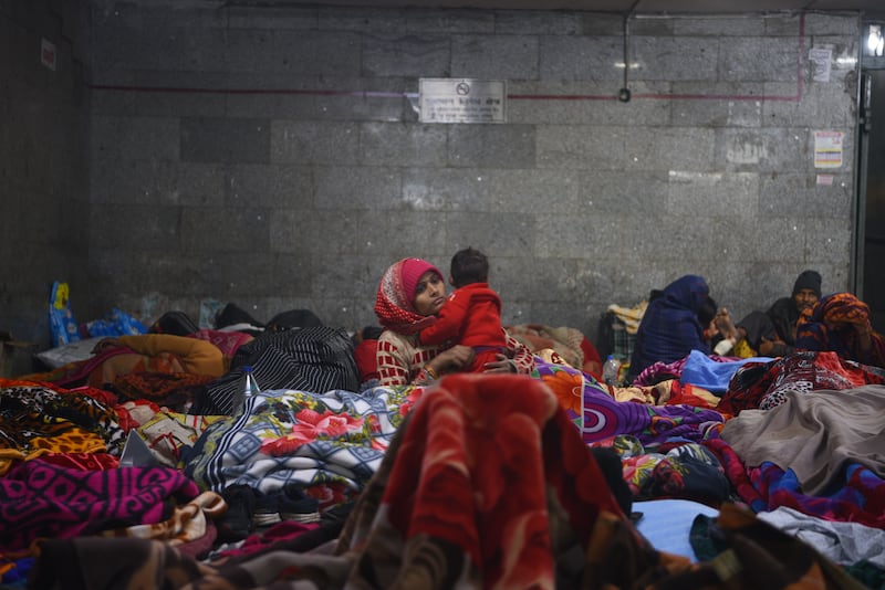 A mother holds her baby among a sea of sleeping people at an underpass in Delhi