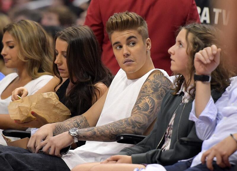 11 May, 2014 file photo shows singer Justin Bieber, centre, watching the Los Angeles Clippers play the Oklahoma City Thunder with his mother Pattie Mallette, second from left, in the first half of Game 4 of the Western Conference semifinal NBA basketball playoff series in Los Angeles. Los Angeles police said Wednesday 14 May, 2014, that they have opened an attempted robbery investigation involving Bieber after receiving a report that the pop singer tried to take property from a person at a Los Angeles family entertainment centre on Monday night. AP