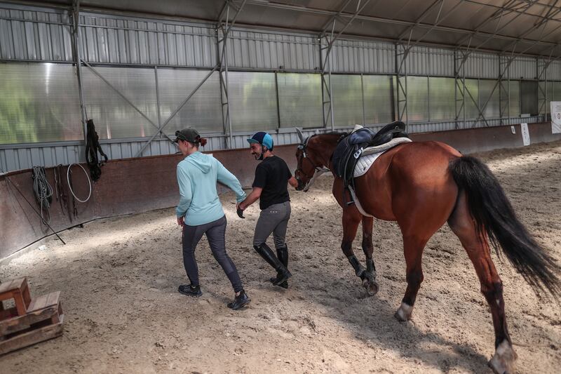Dokuyucu (C) chats with his trainer, Irina Shishigina, at the Equestrian Sports Club in Ankara. "Horses are a light for me," he said.