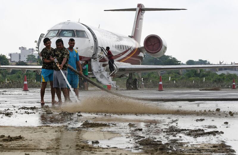 Members of the Nepali Army help clean mud left from floods which hit parts of Biratnagar's domestic airport, some 240 km from Nepal's capital Kathmandu, on August 16, 2017. At least 221 people have died and more than 1.5 million have been displaced by monsoon flooding across India, Nepal and Bangladesh, officials said on August 15, as rescuers scoured submerged villages for the missing. PRAKASH MATHEMA / AFP