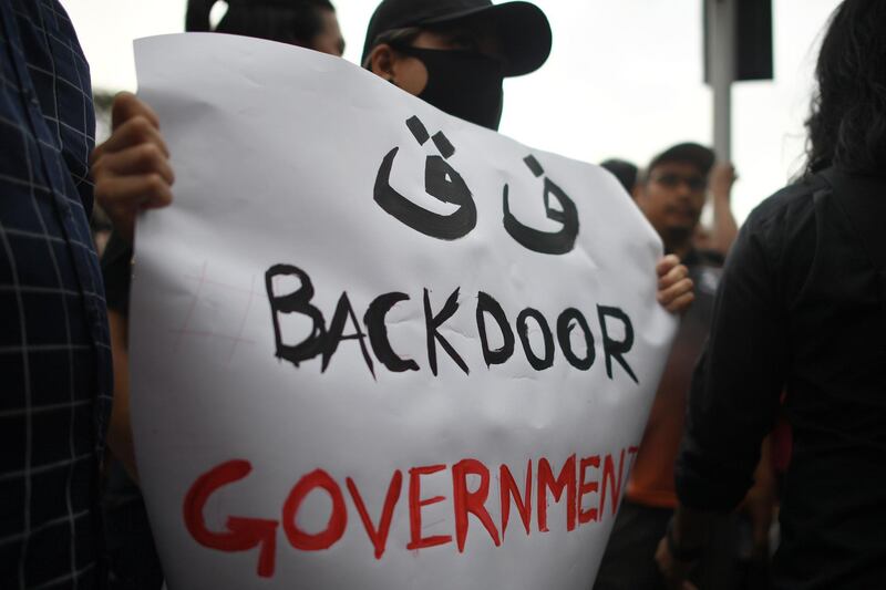 A protester holds a sign while taking part in a demonstration to protest the ejection of the democractically elected government in Kuala Lumpur on March 1, 2020, after Muhyiddin Yassin was sworn in as prime minister following the reformist government's collapse. Muhyiddin, a staunch Muslim nationalist backed by a scandal-mired party, was sworn in as Malaysia's premier on March 1 after a reformist government's collapse, but ex-leader Mahathir Mohamad, 94, slammed the move as illegal. / AFP / Mohd RASFAN
