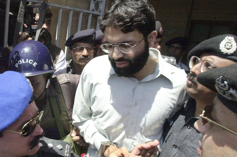 (FILES) In this file taken on March 29, 2002, Pakistani police surround handcuffed Omar Sheikh as he comes out of a court in Pakistan's port city of Karachi.  A Pakistani court on April 2, 2020 overturned the death sentence for British-born militant Ahmed Omar Saeed Sheikh, who had been convicted over the 2002 killing of American journalist Daniel Pearl.  / AFP / Aamir QURESHI
