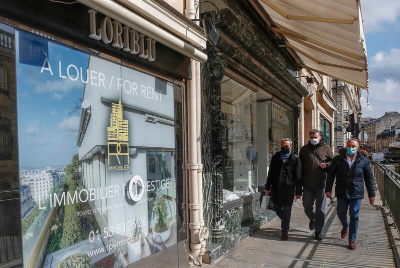People wearing masks to prevent the spread of the coronavirus walk past a vacant boutique for rent in Paris. AP Photo