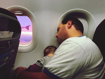 Father With Son Sleeping In Airplane During Sunset. Getty Images