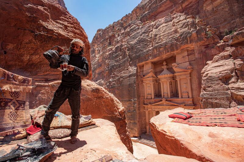 A Bedouin man pours tea for visitors at the Treasury building as they visit the reopened Petra archeological site. EPA