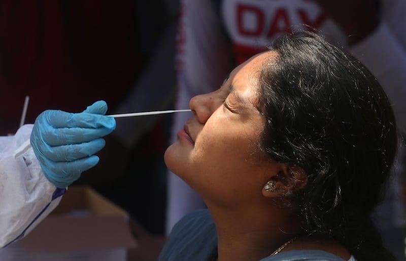 A woman undergoes a swab test at a bus stop in Bangalore, India, on April 7, 2021. EPA