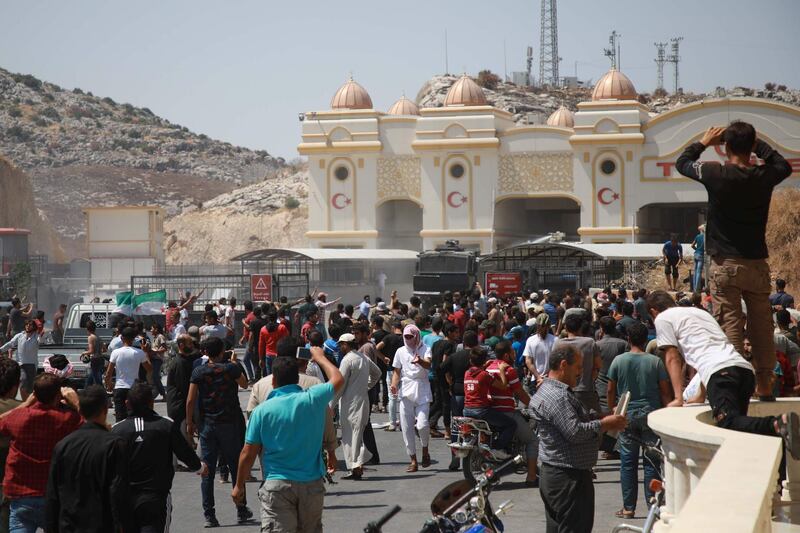 Turkish border guards fire tear gas canisters to disperse a crowd of Syrians from the country's northern countryside gathering for a demonstration by the Bab al-Hawa crossing between Turkey and Syria's northwestern Idlib province on August 30, 2019, calling for Turkey to provide protection or safe passage into Turkish territory.   / AFP / Aaref WATAD
