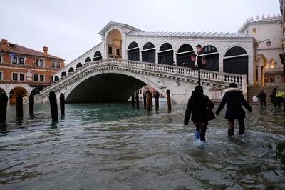 FILE PHOTO: People walk past the Rialto Bridge during high tide as the flood barriers known as Mose are not raised, in Venice, Italy, December 8, 2020. REUTERS/Manuel Silvestri/File Photo