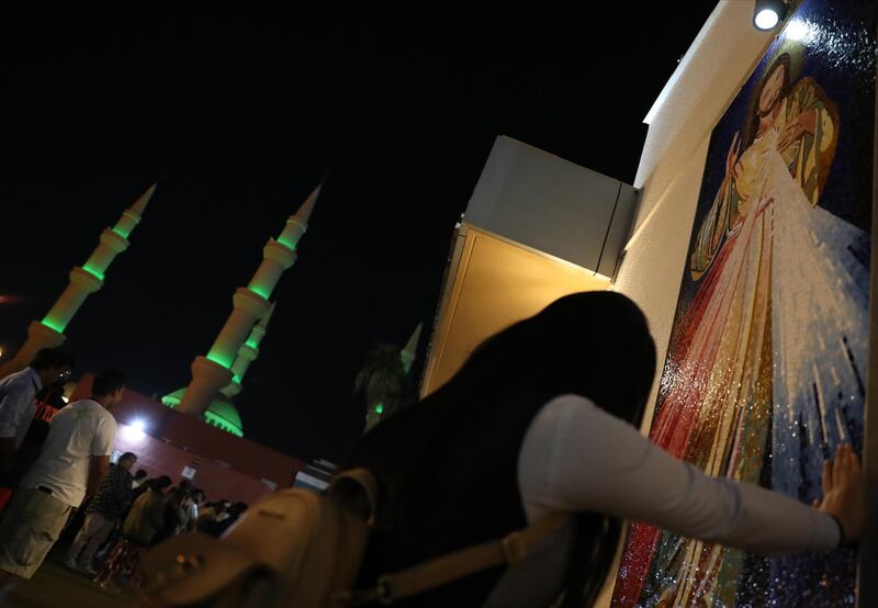 With Mary the mother of Jesus mosque in the background, a worshiper prays in front of a picture of Jesus while attending Christmas Eve prayers at St. Joseph's Cathedral Catholic Church in Abu Dhabi, United Arab Emirates.  EPA
