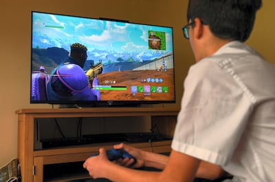 MHN53F A teenager boy plays the hit computer game Fortnite on a large TV on a Playstation 4 console.