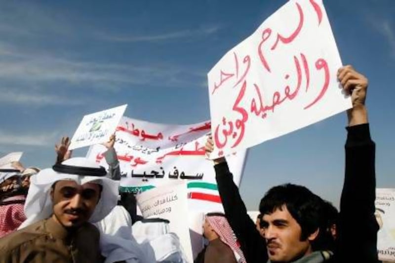 A stateless Arab, known as a bidoon, holds a placard that reads, "We have the same Kuwaiti blood" during a protest demanding citizenship and other rights in Jahra, northwest of Kuwait City, in December 2011.