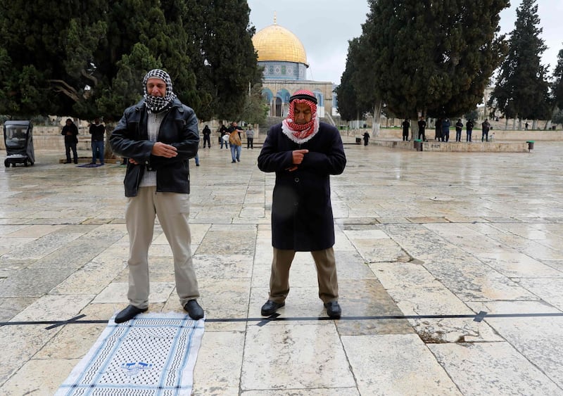 Palestinians perform their Friday prayers in the almost deserted Al-Aqsa mosque compound in the Old City of Jerusalem, after clerics took protective measures and ordered the mosques shut in a bid to stem the spread of the novel coronavirus, on March 20, 2020. Israel has 433 confirmed cases of COVID-19, with another 44 in the occupied Palestinian territories and tens of thousands in self-isolation. / AFP / AHMAD GHARABLI
