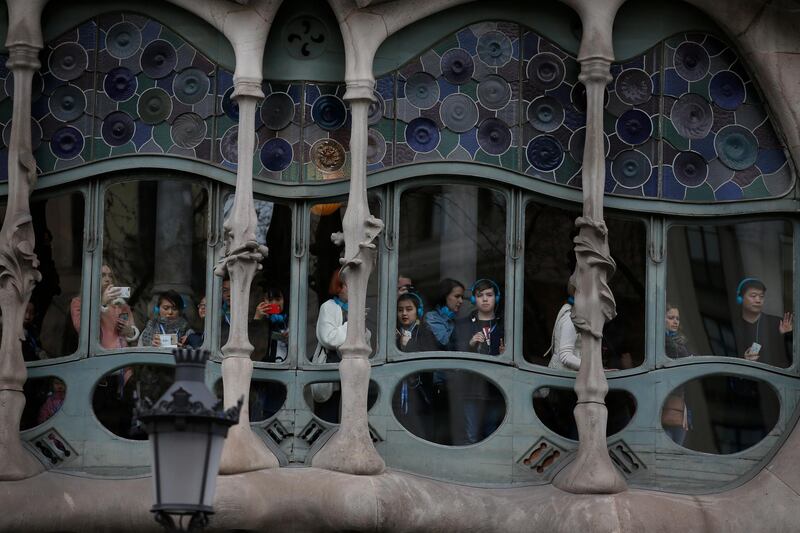 Tourists look out from Antoni Gaudí's Casa Batllo building at a Pro independence demonstration march in support of Catalonian politicians who have been jailed on charges of sedition and the detention of deposed leader of Catalonia's pro-independence party Carles Puigdemont in Barcelona, Spain, on March 25, 2018. Manu Fernandez / AP Photo