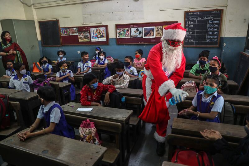 A man dressed as Santa Claus gives sanitiser to pupils as they attend school in Mumbai. AP