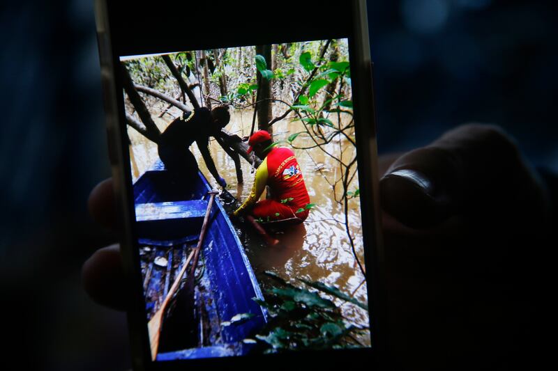 A firefighter holds a phone after a backpack was found during a search for indigenous expert Bruno Pereira and British journalist Dom Phillips in remote Atalaia do Norte, Amazonas state, Brazil. AP