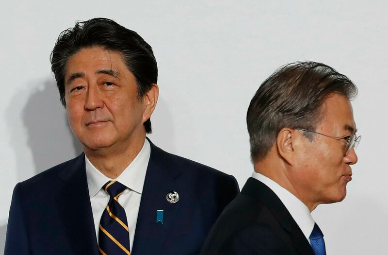 FILE - In this June 28, 2019, file photo, South Korean President Moon Jae-in, right, walks by Japanese Prime Minister Shinzo Abe upon his arrival for a welcome and family photo session at the G-20 leaders summit in Osaka, western Japan. Japan and South Korea, two major U.S. allies, are again at odds, this time over Tokyoâ€™s decision to tighten controls on exports of sensitive materials that are mainly used in computer chips and display screens used in TVs and smartphones. The tensions reflect animosities that have persisted for decades. (Kim Kyung-Hoon/Pool Photo via AP, File)